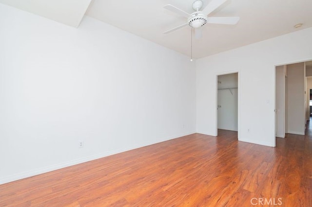 unfurnished bedroom with ceiling fan, a spacious closet, dark hardwood / wood-style flooring, and a closet