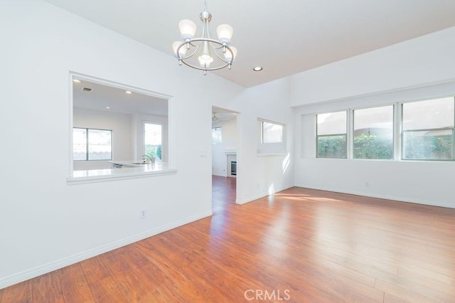 empty room with light hardwood / wood-style flooring, an inviting chandelier, and a healthy amount of sunlight