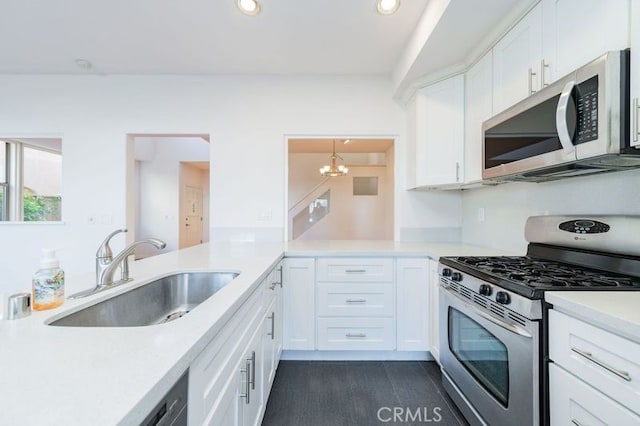 kitchen with kitchen peninsula, sink, stainless steel appliances, and white cabinetry