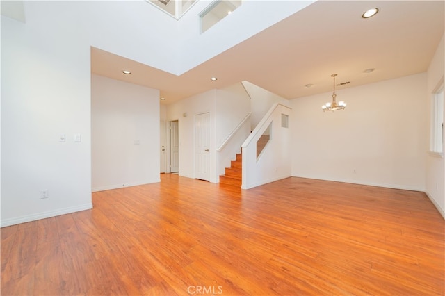 unfurnished living room featuring light wood-type flooring and an inviting chandelier