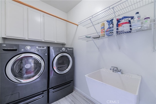 clothes washing area with cabinets, separate washer and dryer, and sink