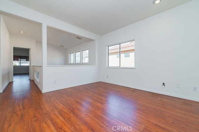 empty room featuring dark wood-type flooring and plenty of natural light