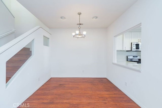 unfurnished dining area featuring dark hardwood / wood-style floors and an inviting chandelier