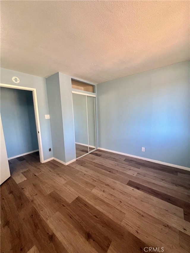 unfurnished bedroom with a closet, dark wood-type flooring, and a textured ceiling