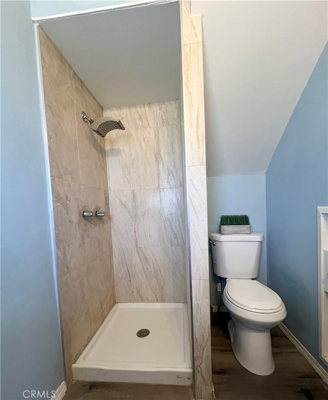 bathroom with toilet, a tile shower, lofted ceiling, and hardwood / wood-style floors