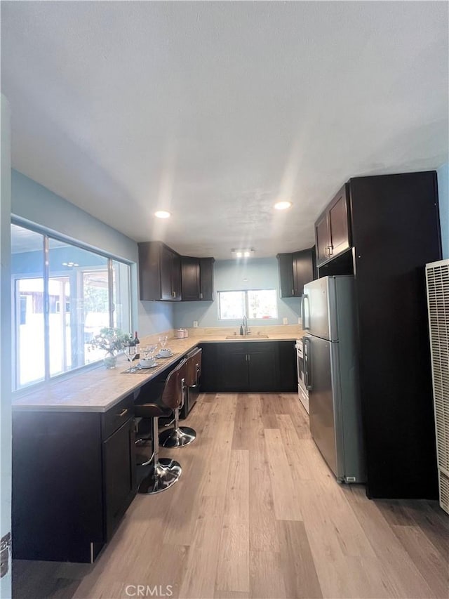 kitchen featuring sink, a healthy amount of sunlight, light hardwood / wood-style flooring, and stainless steel refrigerator