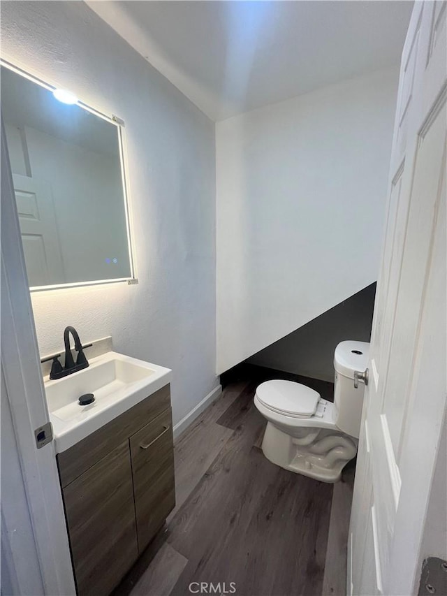 bathroom featuring wood-type flooring, toilet, and vanity