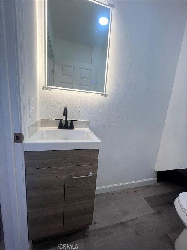 bathroom featuring toilet, vanity, and hardwood / wood-style floors