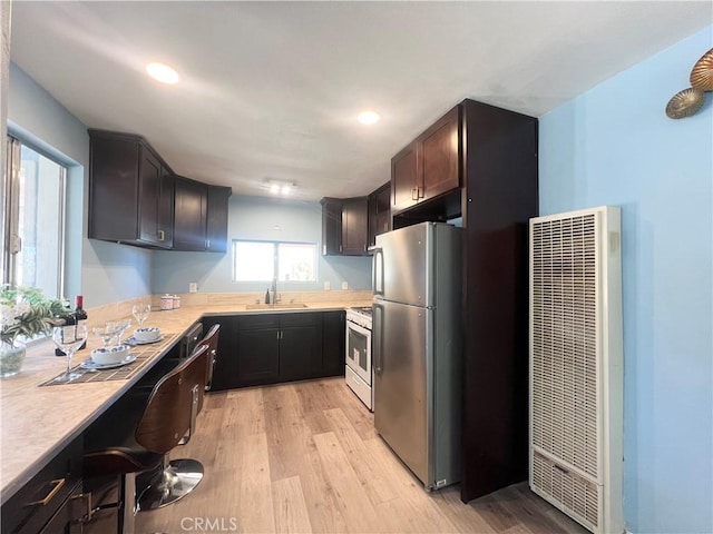 kitchen with sink, stainless steel refrigerator, white gas range, and light hardwood / wood-style floors