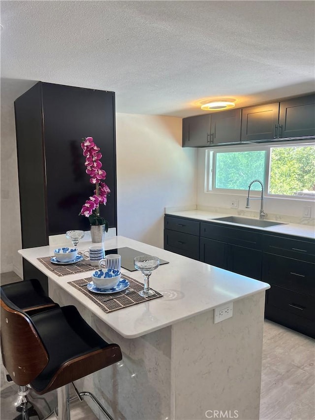 kitchen with a breakfast bar, a textured ceiling, and sink