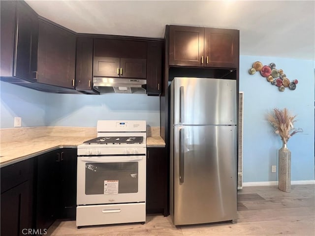 kitchen featuring light hardwood / wood-style floors, dark brown cabinetry, white gas stove, and stainless steel refrigerator