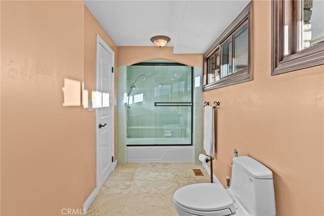 bathroom featuring combined bath / shower with glass door and toilet