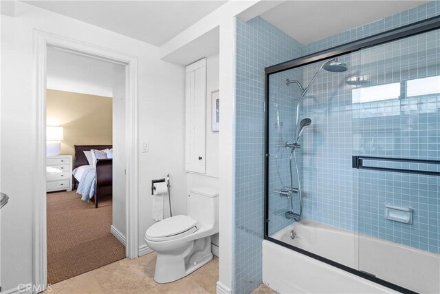 bathroom with combined bath / shower with glass door, tile patterned floors, and toilet