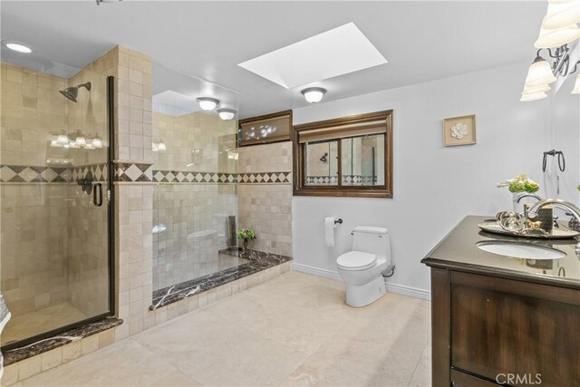 bathroom featuring tile patterned floors, vanity, a skylight, toilet, and a shower with shower door