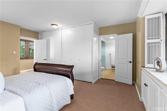 carpeted bedroom featuring a closet and ensuite bath