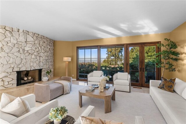 living room with a healthy amount of sunlight, french doors, and a stone fireplace