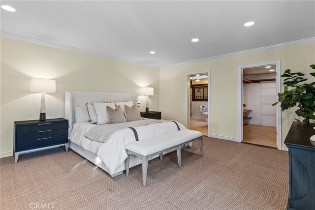 bedroom with carpet, ensuite bath, ornamental molding, a walk in closet, and a closet