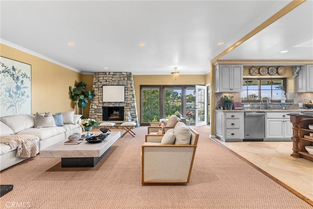 living room featuring crown molding, a stone fireplace, and sink