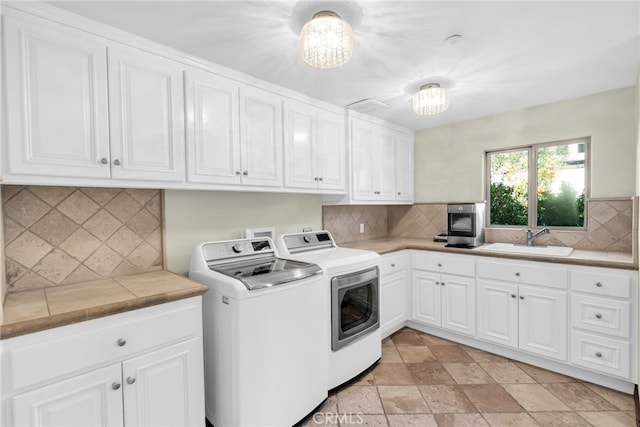 laundry room with washer and dryer, sink, cabinets, and a notable chandelier