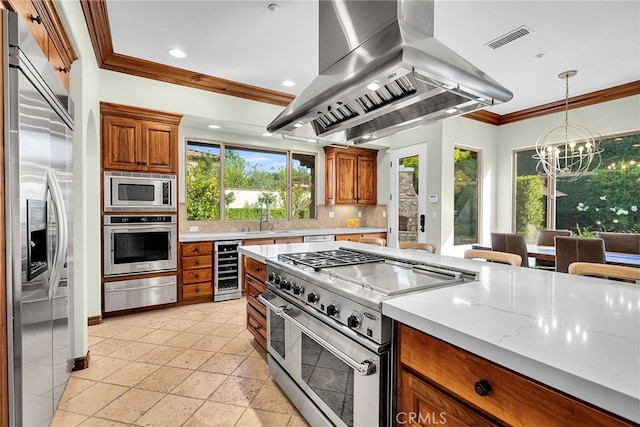 kitchen featuring island exhaust hood, beverage cooler, hanging light fixtures, built in appliances, and a chandelier