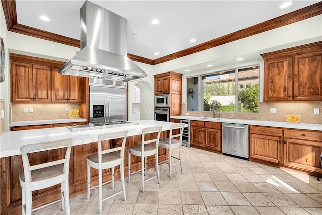 kitchen featuring a center island, island exhaust hood, built in appliances, wine cooler, and a kitchen breakfast bar