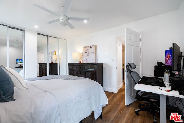 bedroom featuring ceiling fan, dark wood-type flooring, and multiple closets