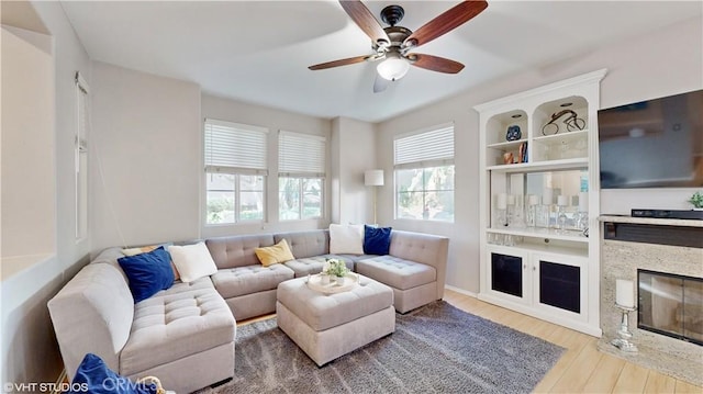 living room with ceiling fan, wood-type flooring, and a fireplace