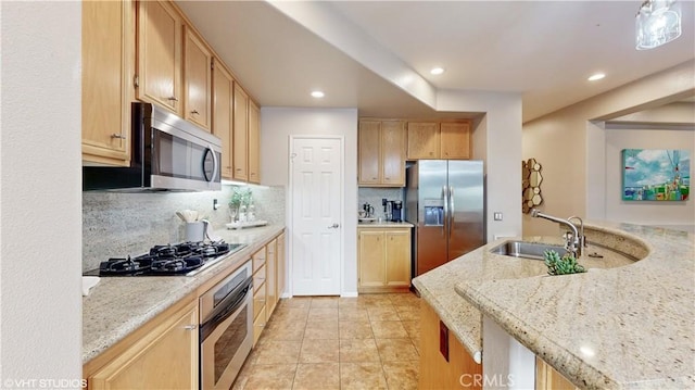 kitchen featuring light brown cabinets, appliances with stainless steel finishes, light stone counters, and tasteful backsplash