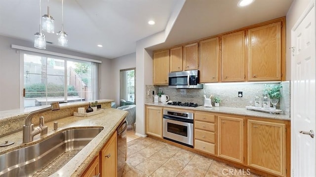 kitchen featuring tasteful backsplash, appliances with stainless steel finishes, light stone countertops, pendant lighting, and a sink