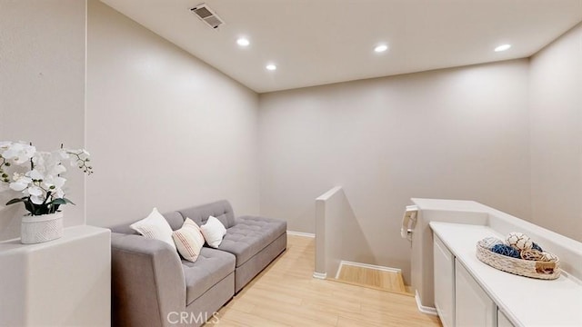 living area with light wood-style floors, recessed lighting, visible vents, and baseboards