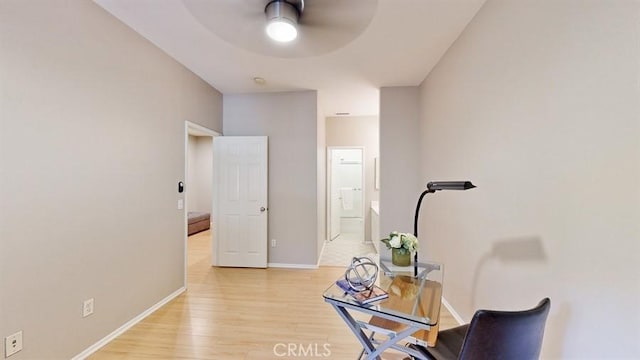 interior space featuring a ceiling fan, light wood-type flooring, and baseboards