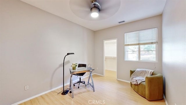 office space featuring a ceiling fan, light wood-type flooring, visible vents, and baseboards