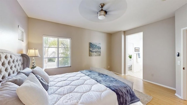 bedroom featuring ceiling fan, ensuite bath, light wood-style flooring, and baseboards