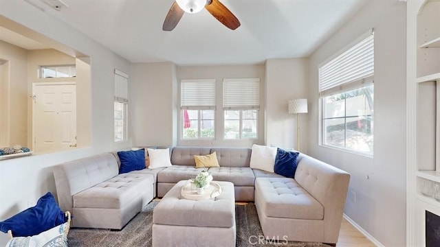 living room with ceiling fan and baseboards