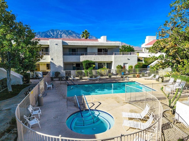 view of swimming pool with a hot tub, a mountain view, and a patio