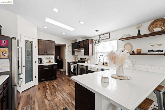 kitchen featuring lofted ceiling with skylight, a breakfast bar, sink, appliances with stainless steel finishes, and pendant lighting