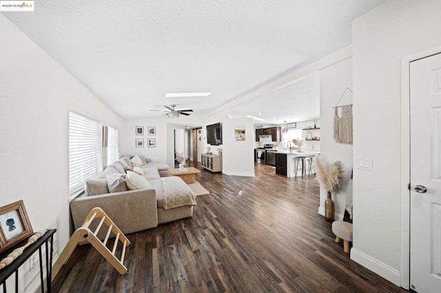 living room with dark wood-type flooring, ceiling fan, and vaulted ceiling