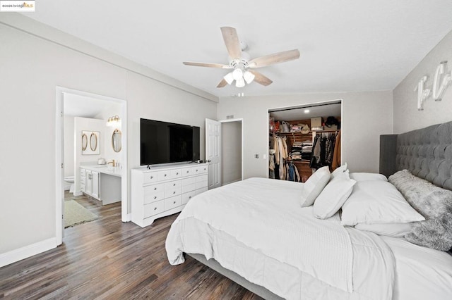 bedroom featuring connected bathroom, a spacious closet, dark hardwood / wood-style flooring, a closet, and ceiling fan