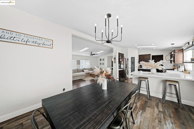 dining space with dark hardwood / wood-style flooring and ceiling fan with notable chandelier