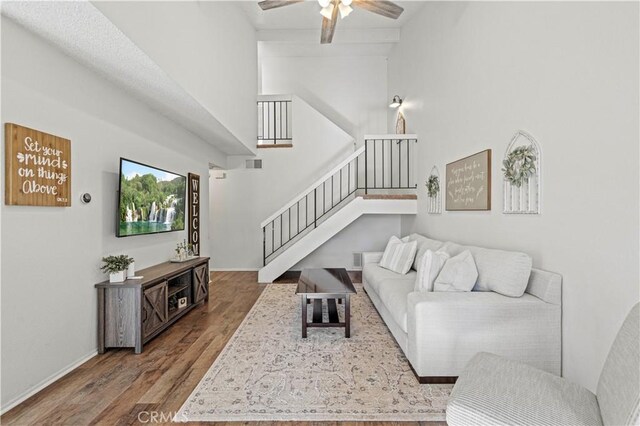 living room with ceiling fan, a high ceiling, and hardwood / wood-style floors