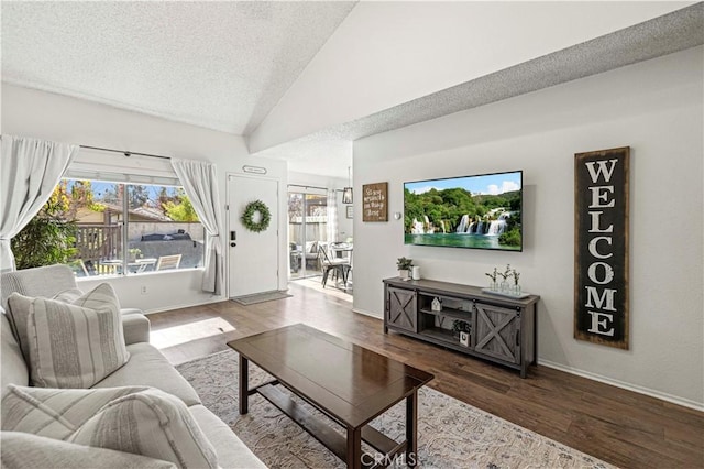 living room featuring a textured ceiling, wood-type flooring, a healthy amount of sunlight, and vaulted ceiling