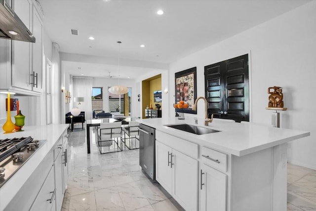 kitchen with appliances with stainless steel finishes, white cabinetry, sink, hanging light fixtures, and a kitchen island with sink