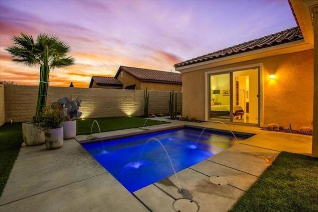 pool at dusk featuring a patio and pool water feature