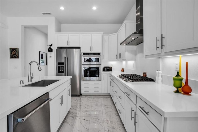 kitchen featuring stainless steel appliances, white cabinetry, sink, and wall chimney range hood