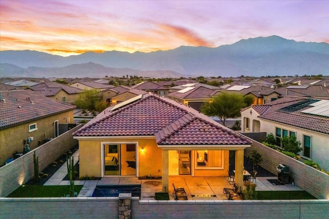 back house at dusk with a mountain view and a patio area