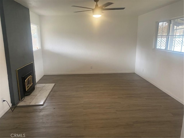 unfurnished living room featuring ceiling fan, dark wood-type flooring, and a wood stove