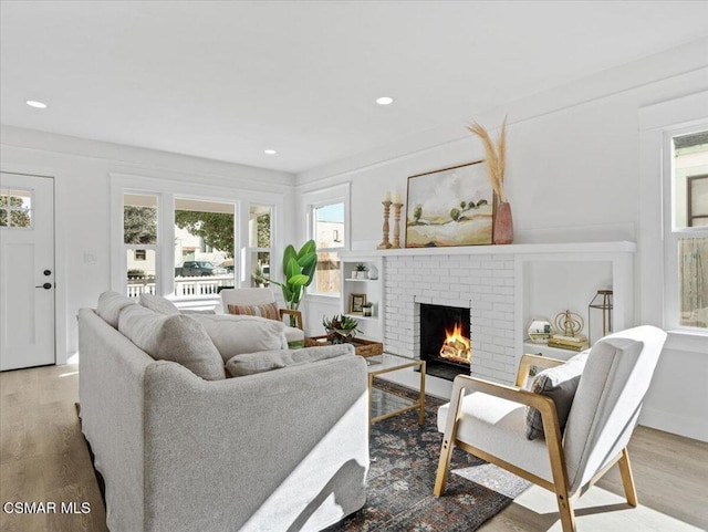 living room featuring a brick fireplace and light hardwood / wood-style flooring