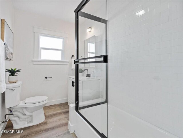 full bathroom with toilet, hardwood / wood-style floors, vanity, and shower / bath combination with glass door