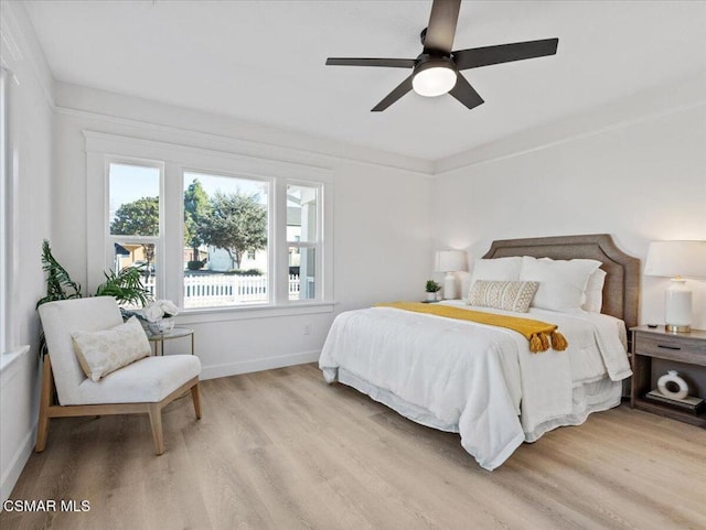 bedroom with ceiling fan, multiple windows, and light hardwood / wood-style flooring