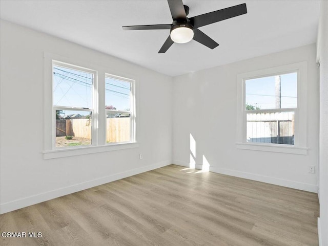 spare room featuring ceiling fan, a healthy amount of sunlight, and light wood-type flooring